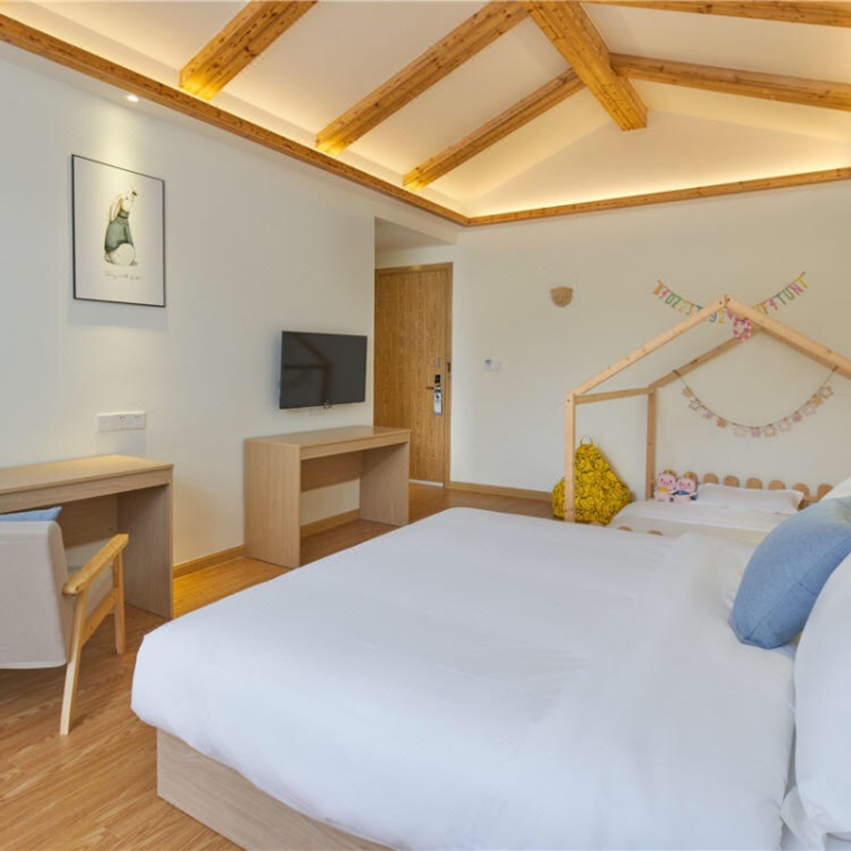 A bedroom with a wooden ceiling, a bed, a desk, and a television.