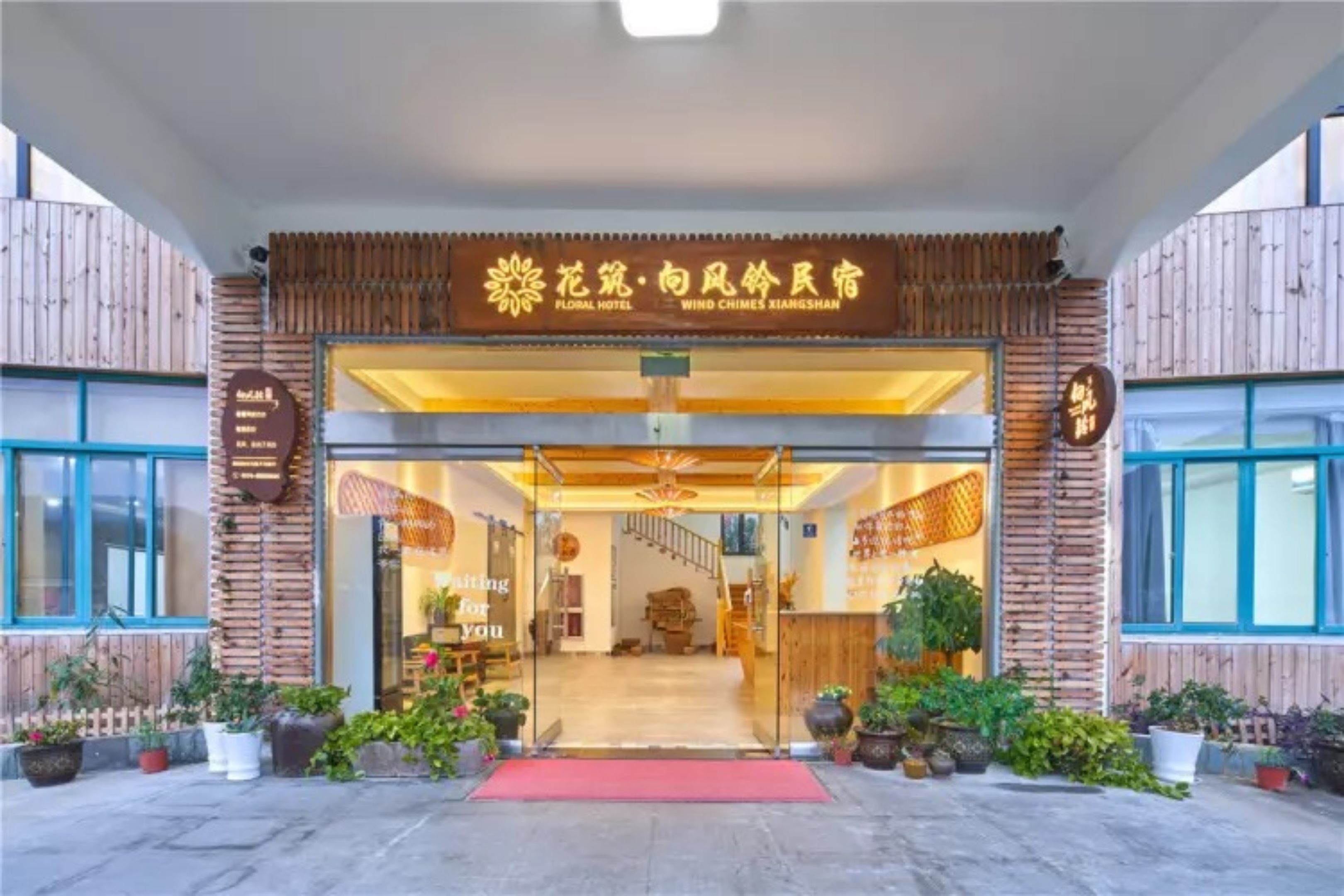A entrada do Hotel Floral, com um tapete vermelho que leva à área de recepção.