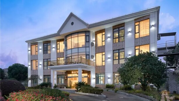 Un hôtel à plusieurs étages, doté d’un design moderne, comprenant une cour intérieure et de nombreuses fenêtres de différents types.