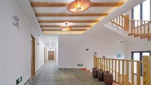 Un couloir avec des poutres en bois, un escalier avec des rampes en bois et un luminaire au plafond.
