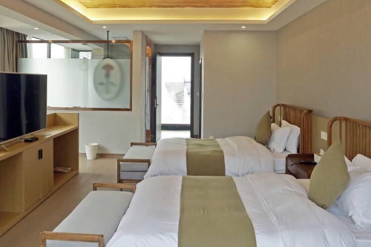 Habitación de hotel con dos camas, televisión, escritorio y un ventanal grande.