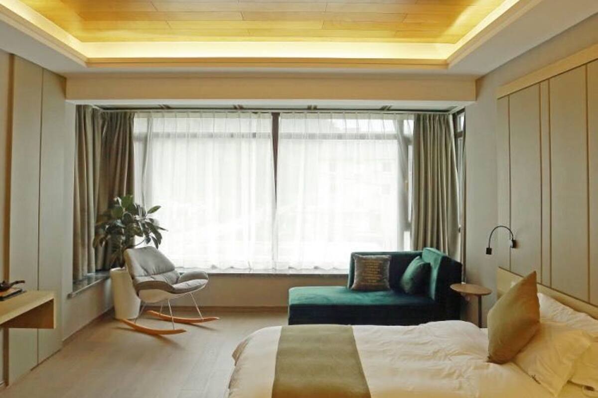 Un dormitorio moderno con una cama grande, un sofá verde, una mesita y una silla.