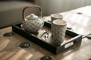 A tray with a teapot, two cups, and a spoon on a wooden surface.