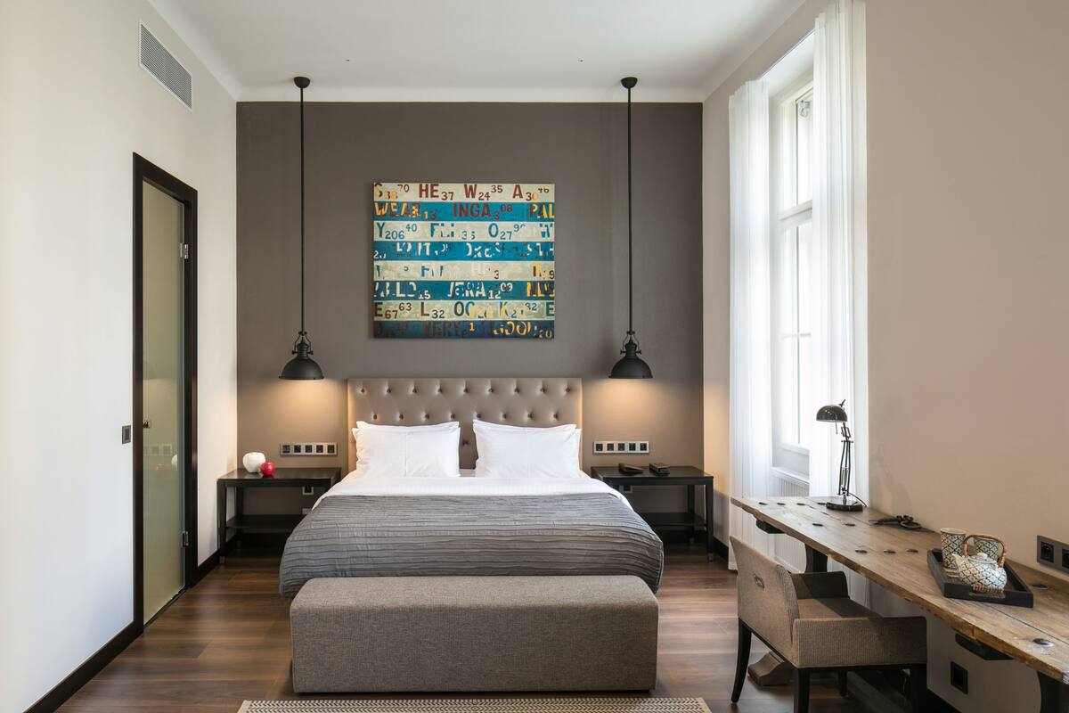 A modern bedroom with a large bed, two bedside tables, a bench, and a wall art piece.