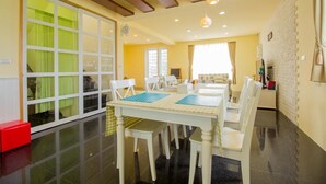 A dining area with a white table and chairs, a red trash bin, and a brick wall. - We Kids BB (Wujie)