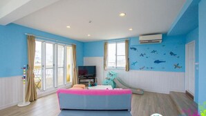A spacious room with a large sofa, a television, and a slide. - We Kids BB (Wujie)