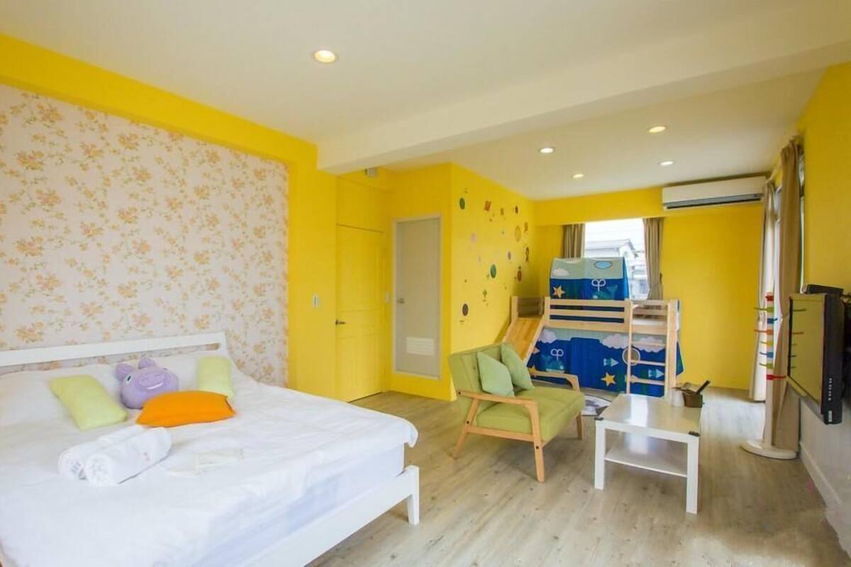 A bedroom with a bed, a chair, a small table, and a bunk bed.