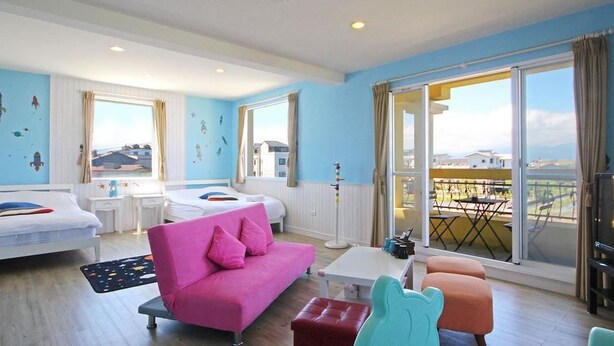 A bright room with a pink sofa, two beds, a table, and a balcony with a view. - We Kids BB (Wujie)