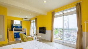A bright yellow room with a bed, a small table, a TV, and a window with a view of the outside. - We Kids BB (Wujie)