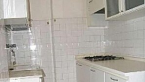 A kitchen with white cabinets, a countertop, and a stove. - La Zattera (Lignano Sabbiadoro)