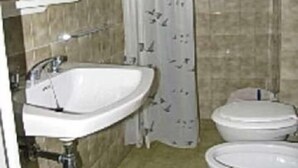 A bathroom with a sink, two toilets, and a shower curtain. - La Zattera (Lignano Sabbiadoro)