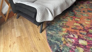 A cozy room with a bed, a patterned rug, a wooden lattice wall, and a small table with a kettle.