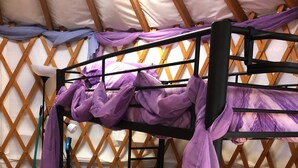 A bed with a black metal frame, purple bedding, and a white pillow.