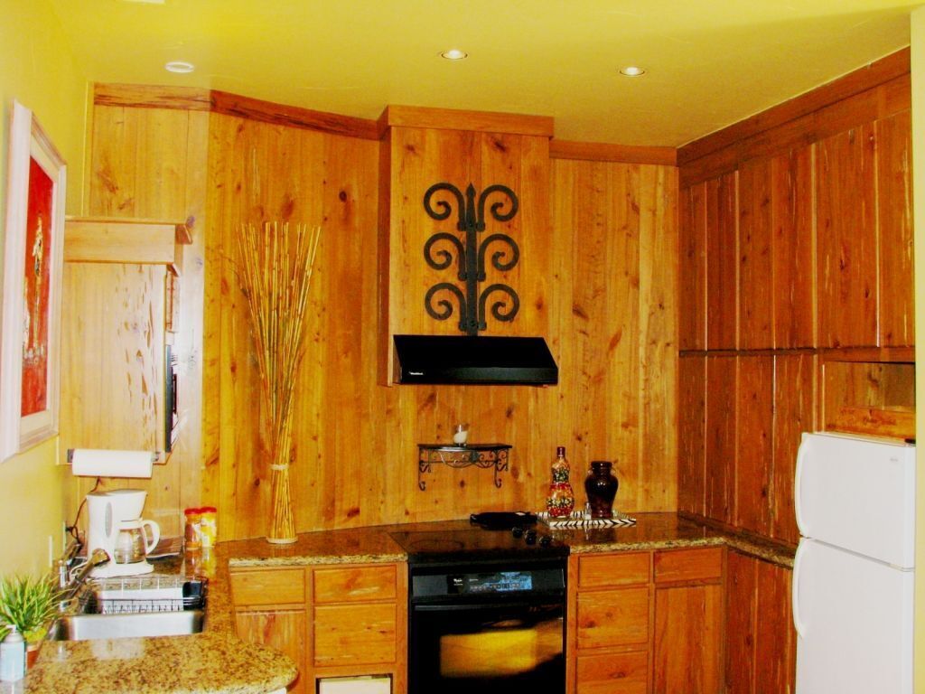 A kitchen with wooden cabinets, a stove, a sink, and a refrigerator.