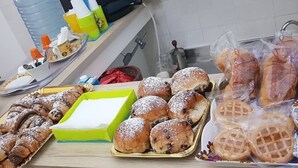 A buffet table with various baked goods, including pastries and bread rolls, and a green box of sugar. - Al Baglio di Maqueda (Palermo)