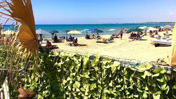 Una playa con sombrillas y gente.