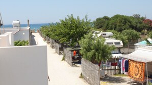 Una hilera de vehículos recreativos estacionados a lo largo de una playa arenosa bajo un cielo despejado.