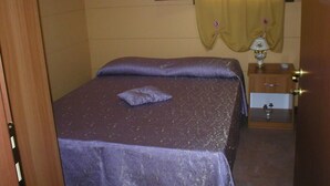 Un dormitorio con dos camas, una mesita de noche con lámpara y un espejo en la pared.