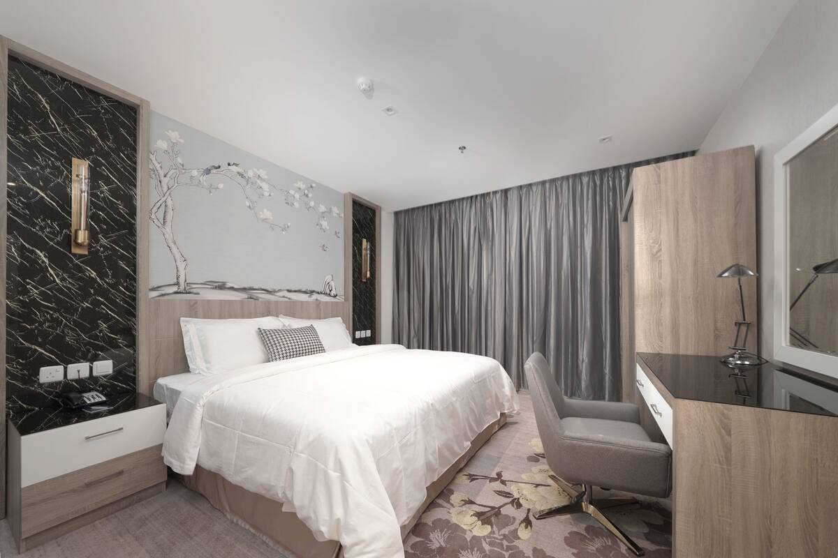A modern bedroom with a large bed, a desk, and a chair.