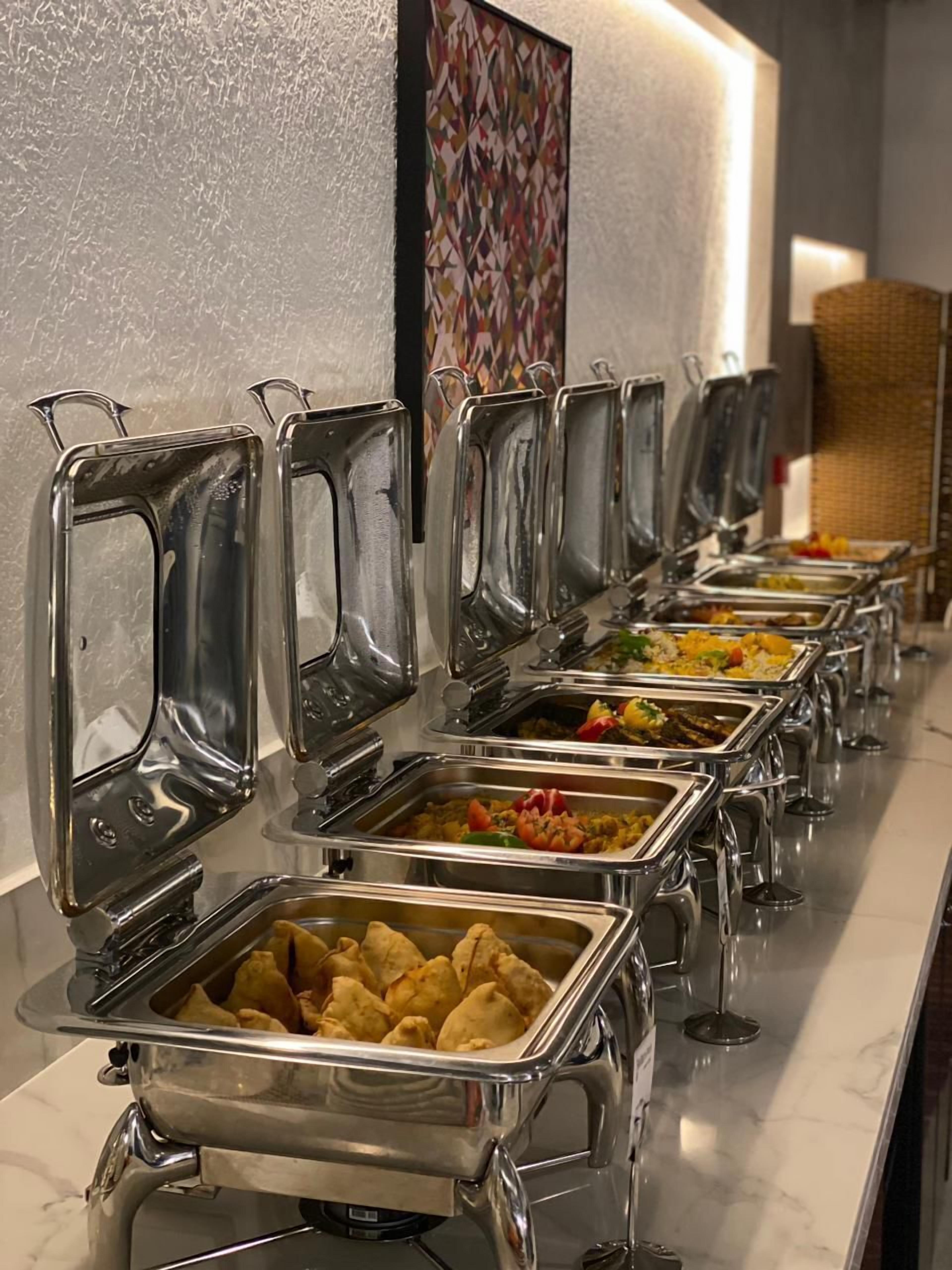 A buffet line with various food stations, including a section with samosas.