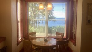 A dining area with a table and four chairs, a window with blinds, and a hanging light fixture.
