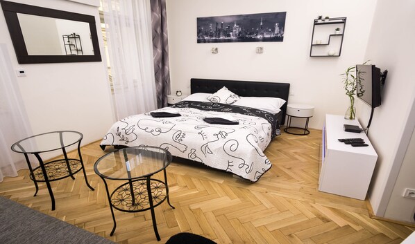 Una camera da letto ordinata con un letto, due comodini, un piccolo armadietto bianco e un televisore su un mobile.