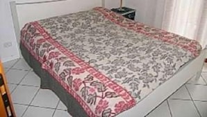A bedroom with a bed, a nightstand, and a lamp. - Lucerna (Lignano Sabbiadoro)
