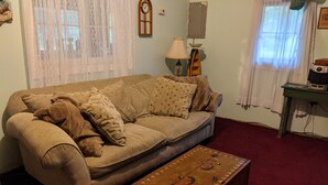 A living room with a sofa, a patterned coffee table, a lamp, and a clock on the wall.
