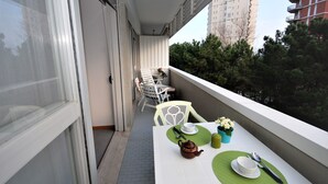 A balcony with a table set for two, featuring a teapot, cups, and a green placemat. - Palme Residence (Lignano Sabbiadoro)