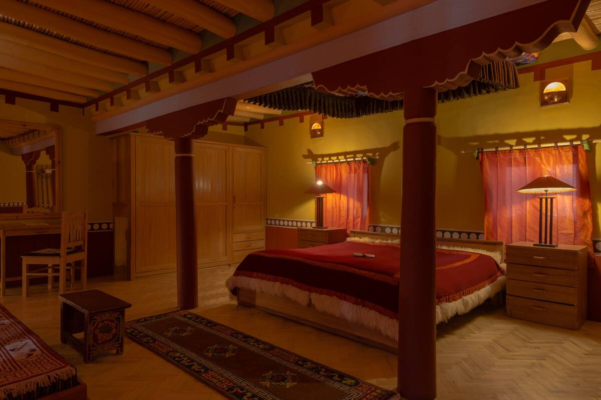 A traditional room with a bed, wooden furniture, and a decorative ceiling.