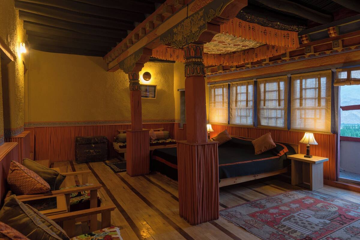 A traditional room with wooden furniture, a bed, a small table, and a window with curtains.