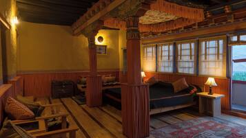 A traditional room with wooden furniture, a bed, a small table, and a window with curtains.