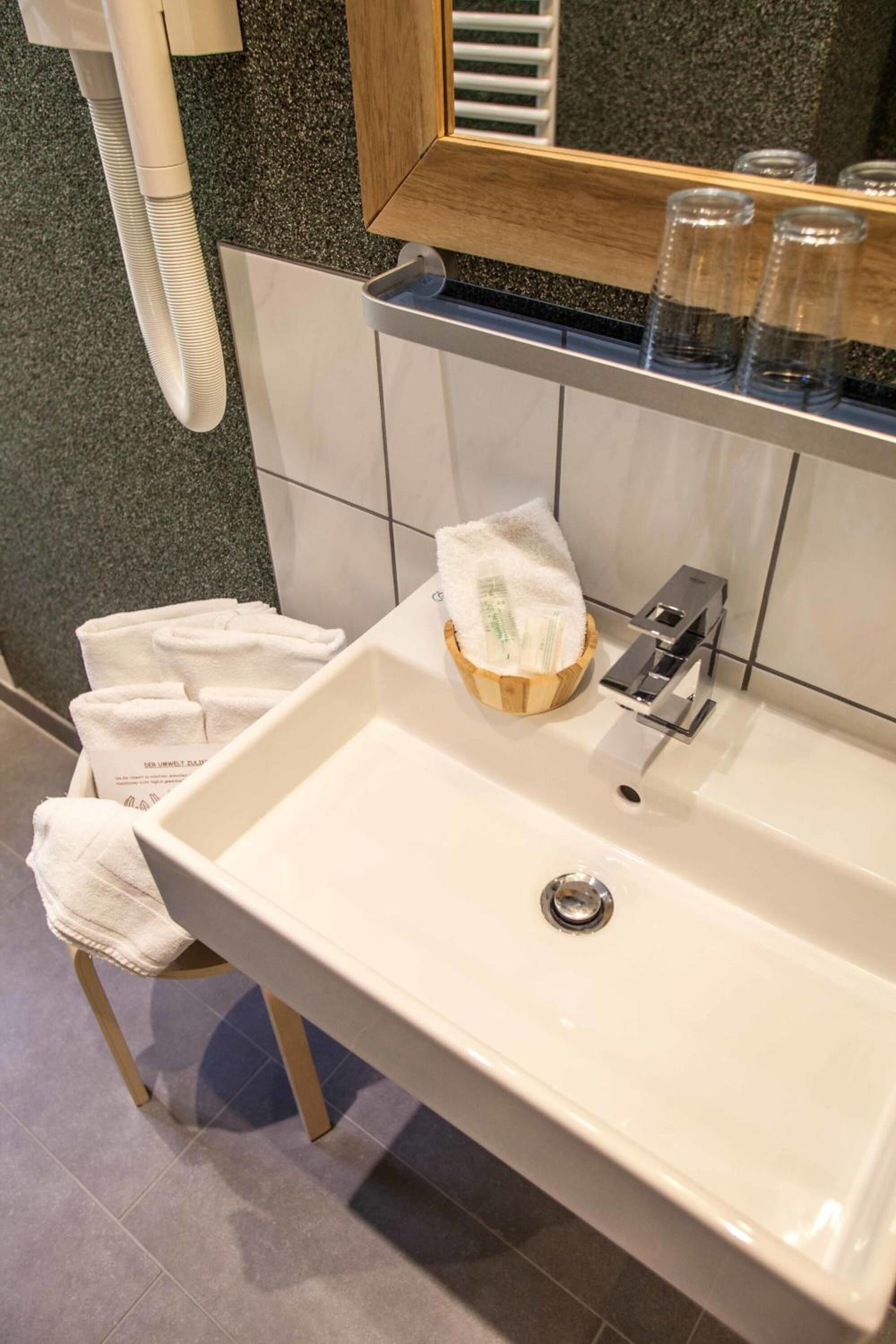 A bathroom with a white sink, a mirror, and a towel rack.