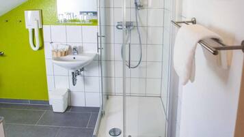Un baño moderno con ducha envuelta en vidrio, lavamanos con espejo e inodoro.