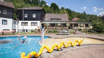Una piscina con tobogán y dos niños jugando.
