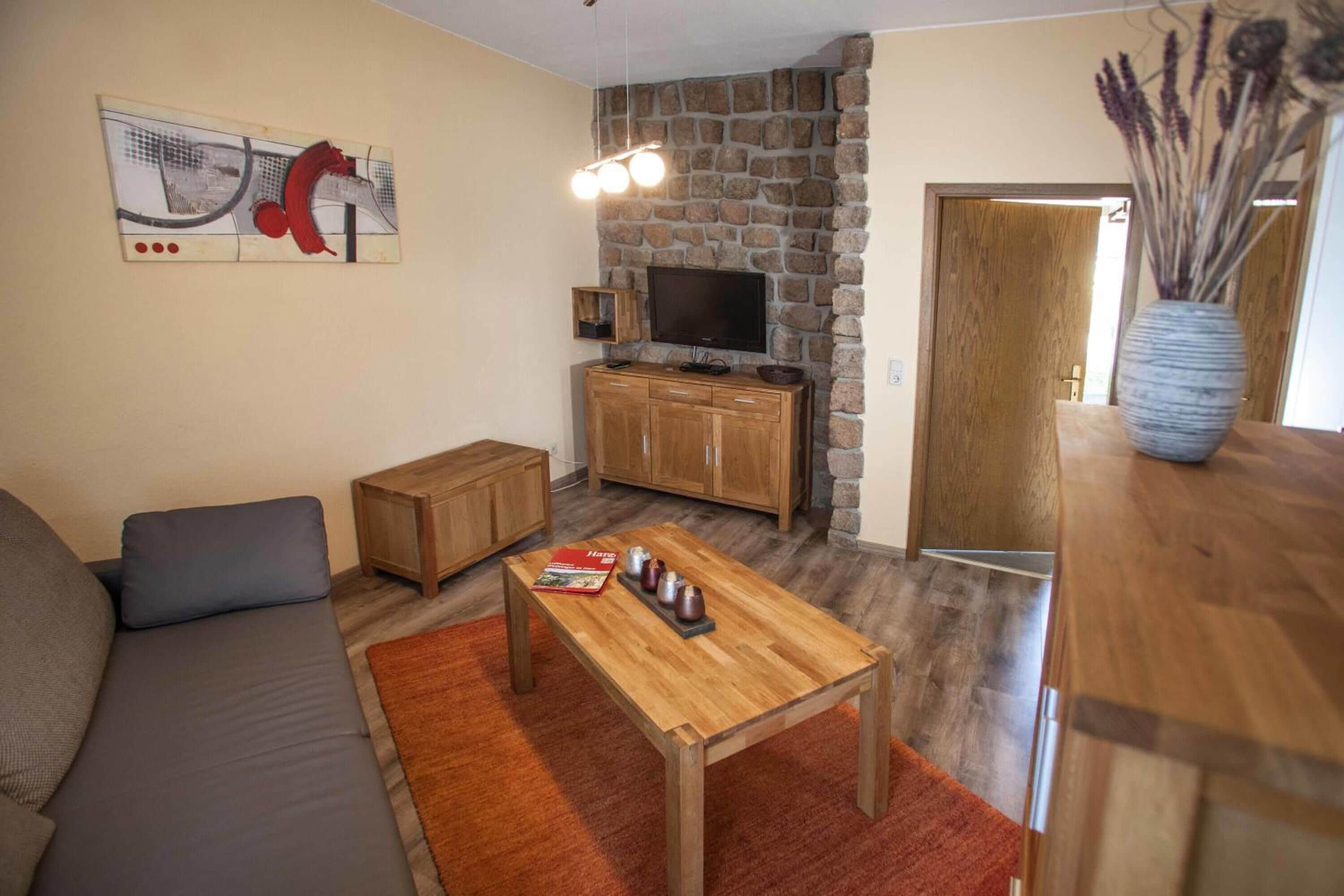 A living room with a sofa, a coffee table, a TV, and a stone wall.