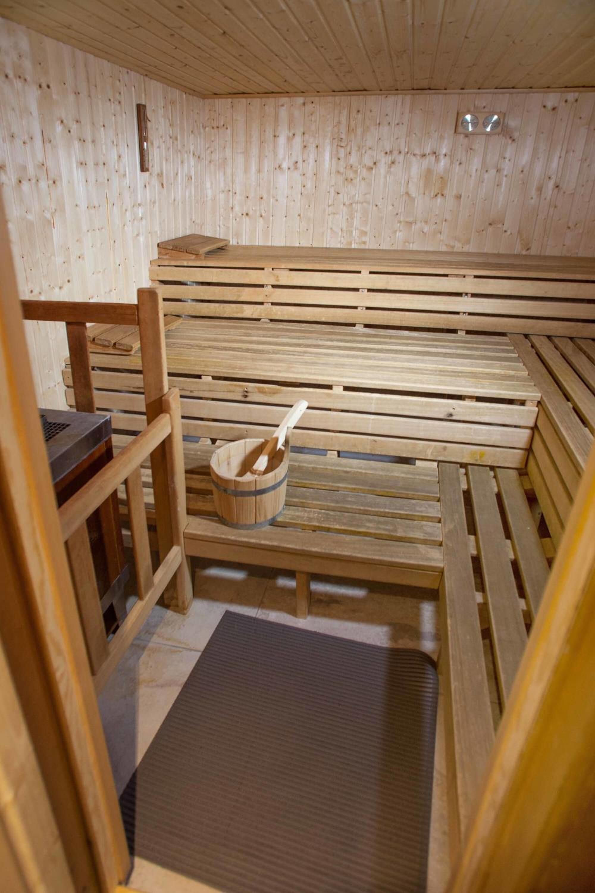 Una sauna de madera con bancos y un balde de madera con una cuchara.