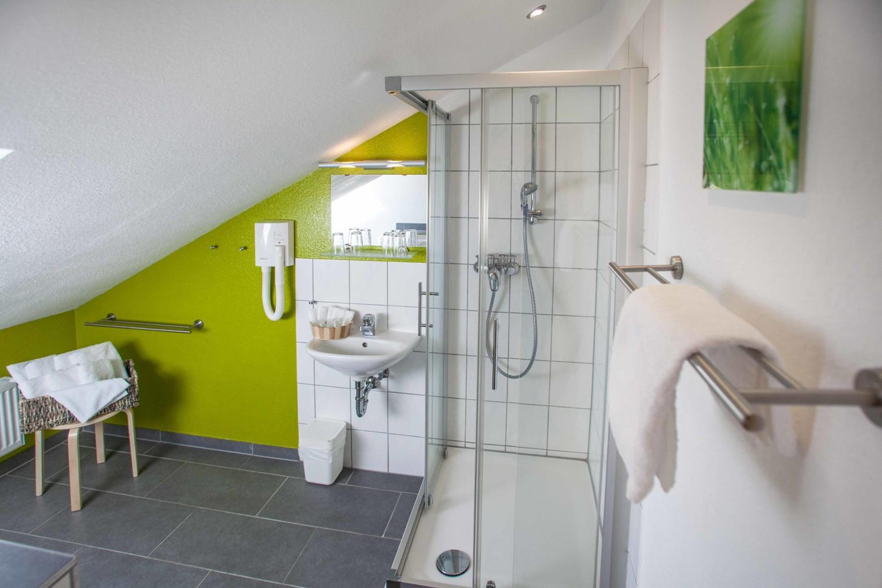 Ein modernes Badezimmer mit Dusche, Waschbecken und Handtuchhalter.