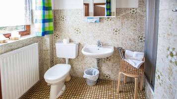 Une salle de bain comprenant des toilettes, un lavabo et un espace douche.