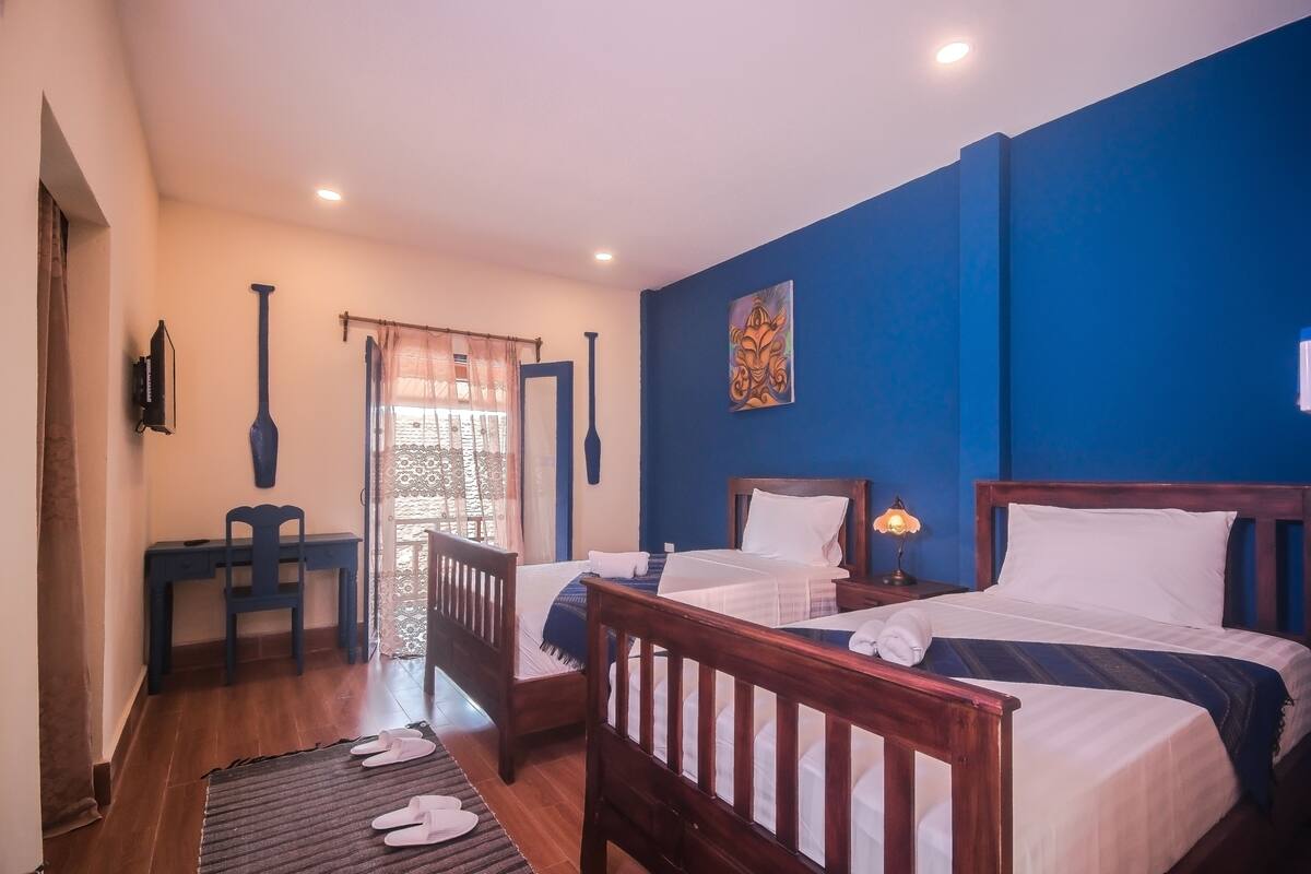 A bedroom with two beds, a desk, and a chair.