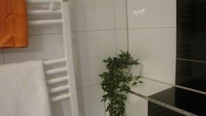 A bathroom with a white towel rack, a white towel, and a green plant. - Milano Hotel (Hamburg)