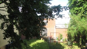 A grassy outdoor area with a swing set, a brick building, and trees. - Milano Hotel (Hamburg)