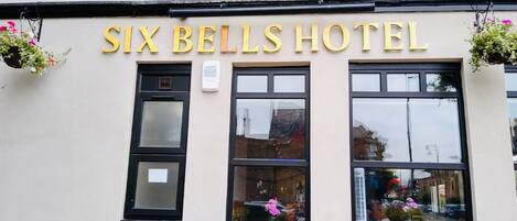 The exterior of the Six Bells Hotel with its name displayed in large letters above the entrance.
