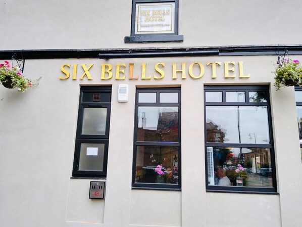The exterior of the Six Bells Hotel with its name displayed in large letters above the entrance. - Six Bells Hotels (Enfield)
