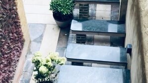 A stone staircase leading up to a brick wall, surrounded by potted plants and outdoor seating. - Six Bells Hotels (Enfield)