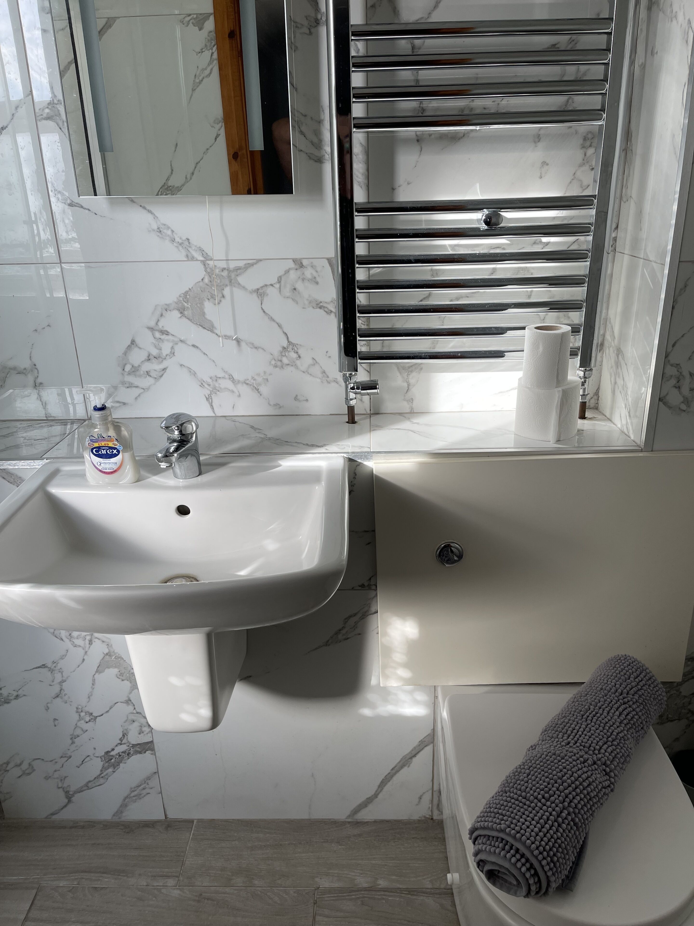 A bathroom with a white sink, a mirror, a towel, and a toilet.