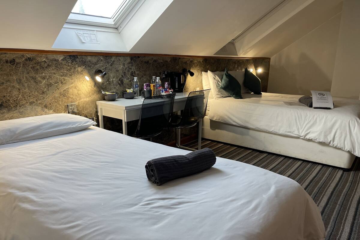 Ein Hotelzimmer mit zwei Betten, einem Schreibtisch und einem Oberlicht.