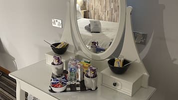 A white vanity with a large mirror, a bowl, and various toiletries.