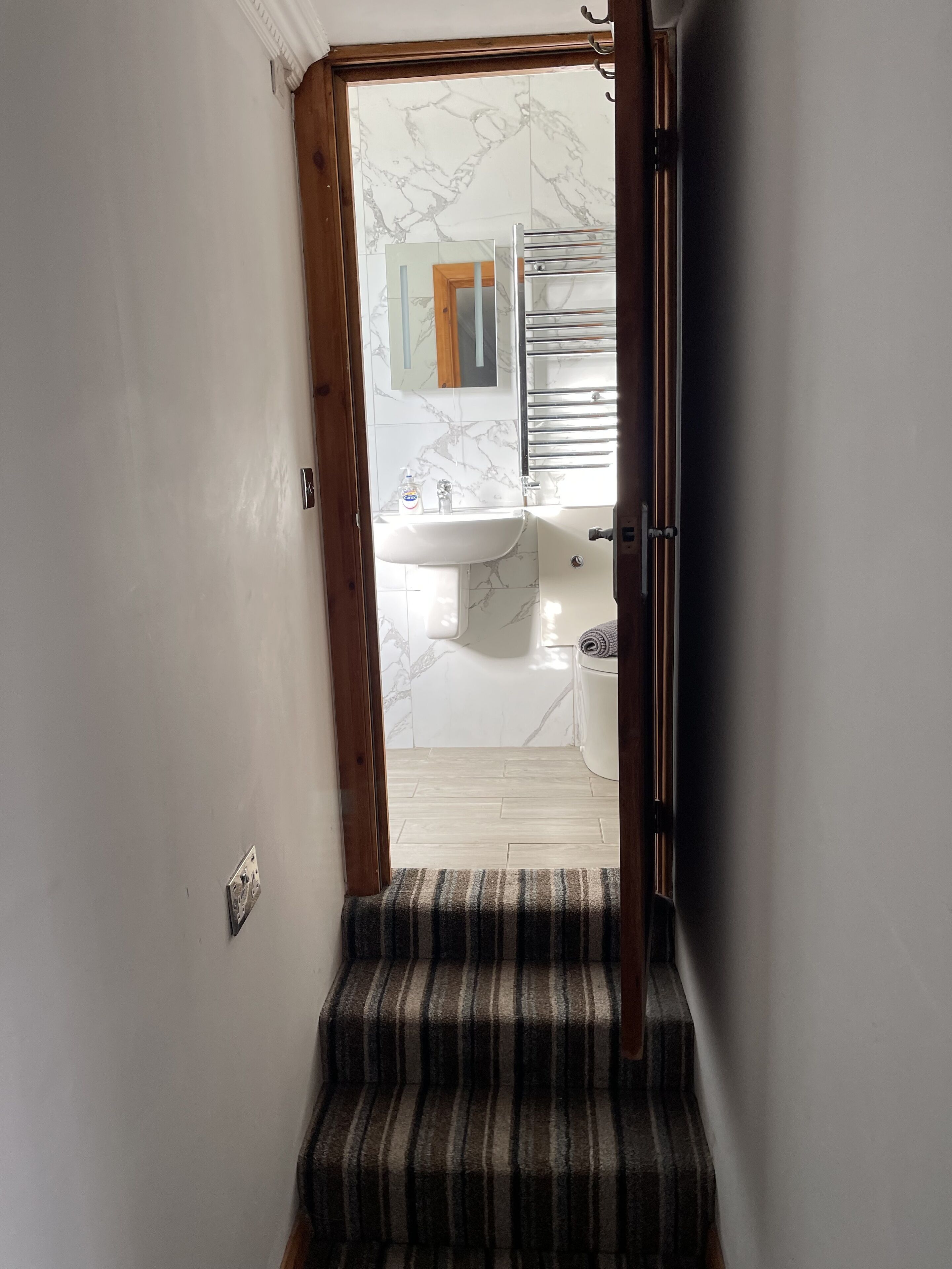 Une salle de bain avec un mur en marbre, un lavabo et un miroir.