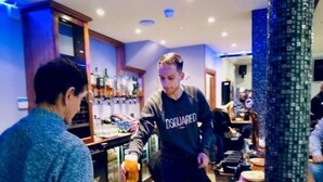 A bar area with a bartender serving drinks. - Six Bells Hotels (Enfield)